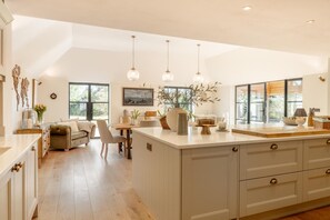A spacious kitchen with a large island, wooden cabinets, and pendant lighting. - 4 Bed in Beccles (oc-v46416) (Beccles)