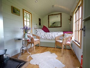 A cozy room with a bed, two wicker chairs, a small table, and a white fur rug. - 1 Bed in Abergavenny (oc-42846) (Llangenny)