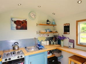 A compact kitchen with a gas stove, sink, and a clock on the wall. - 1 Bed in Abergavenny (oc-42846) (Llangenny)