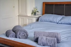 Ein ordentlich bezogenes Bett mit blauer Bettwäsche und zwei aufgerollten Handtüchern.