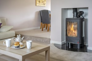 Ein gemütliches Wohnzimmer mit Kamin, einem Tisch mit Tassen und Gebäck sowie einer bequemen Couch.