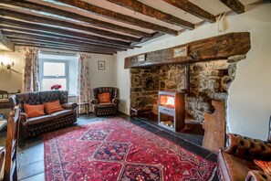 A cozy living room with a stone fireplace, a leather sofa, and a patterned rug. - 4 Bed in Dolgellau (oc-g46068) (Brithdir and Llanfachreth)