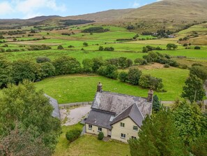 A rural house with a stone roof, surrounded by green fields and trees. - 4 Bed in Dolgellau (oc-g46068) (Brithdir and Llanfachreth)