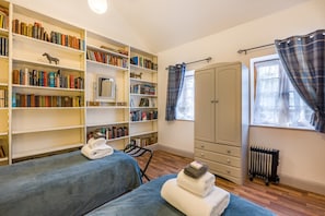A room with two beds, a wardrobe, a radiator, and a bookshelf filled with books. - 2 Bed in Lakenheath (oc-t46347) (Lakenheath)