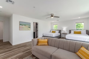 A modern hotel room with a sofa, two beds, a ceiling fan, and a painting on the wall. - Oldtown Escape (Scottsdale)