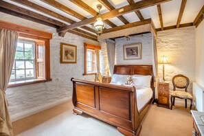 A bedroom with a wooden four-poster bed, a nightstand, a chair, and a lamp. - 5 Bed in Betws Garmon (oc-bibd) (Betws Garmon)