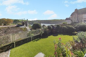 A well-maintained lawn with a stone wall and a view of a body of water and distant hills. - 3 Bed in Fowey (oc-h46394) (Fowey)