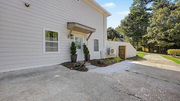 A two-story house with a front porch, a small garden, and a driveway.