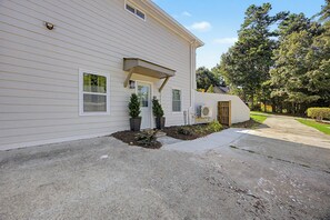 A two-story house with a front porch, a small garden, and a driveway.