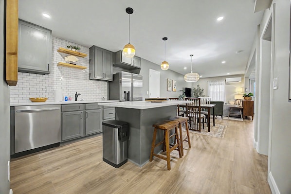 A modern kitchen with stainless steel appliances, a central island, and wooden stools.