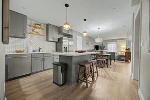 Una cocina moderna con armarios grises, un refrigerador de acero inoxidable e una isla central con taburetes.