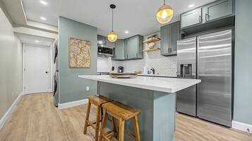 A modern kitchen with a central island, stainless steel appliances, and wooden bar stools.