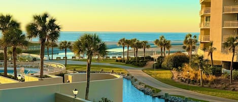 A hotel with a pool, a view of the ocean, and a parking area.