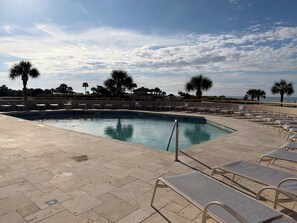 A swimming pool with lounge chairs and palm trees. - Relaxing Oceanview Beach Retreat in Ocean Creek (Myrtle Beach)