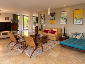 A modern living room with a sofa, chairs, a TV, and artwork on the walls. - Spacious loft at the foot of Pedra da Gávea.  Gated community with 24-hour security. (Rio de Janeiro)