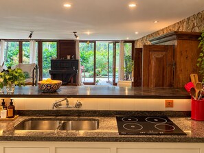 A modern kitchen with a granite countertop, stainless steel sink, and a black induction cooktop. - Spacious loft at the foot of Pedra da Gávea.  Gated community with 24-hour security. (Rio de Janeiro)