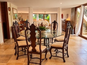 A dining area with a glass table surrounded by ornate chairs, a potted plant, and a view of a staircase. - Spacious loft at the foot of Pedra da Gávea.  Gated community with 24-hour security. (Rio de Janeiro)
