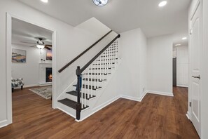 Um interior moderno com escada de madeira, paredes brancas e lareira.