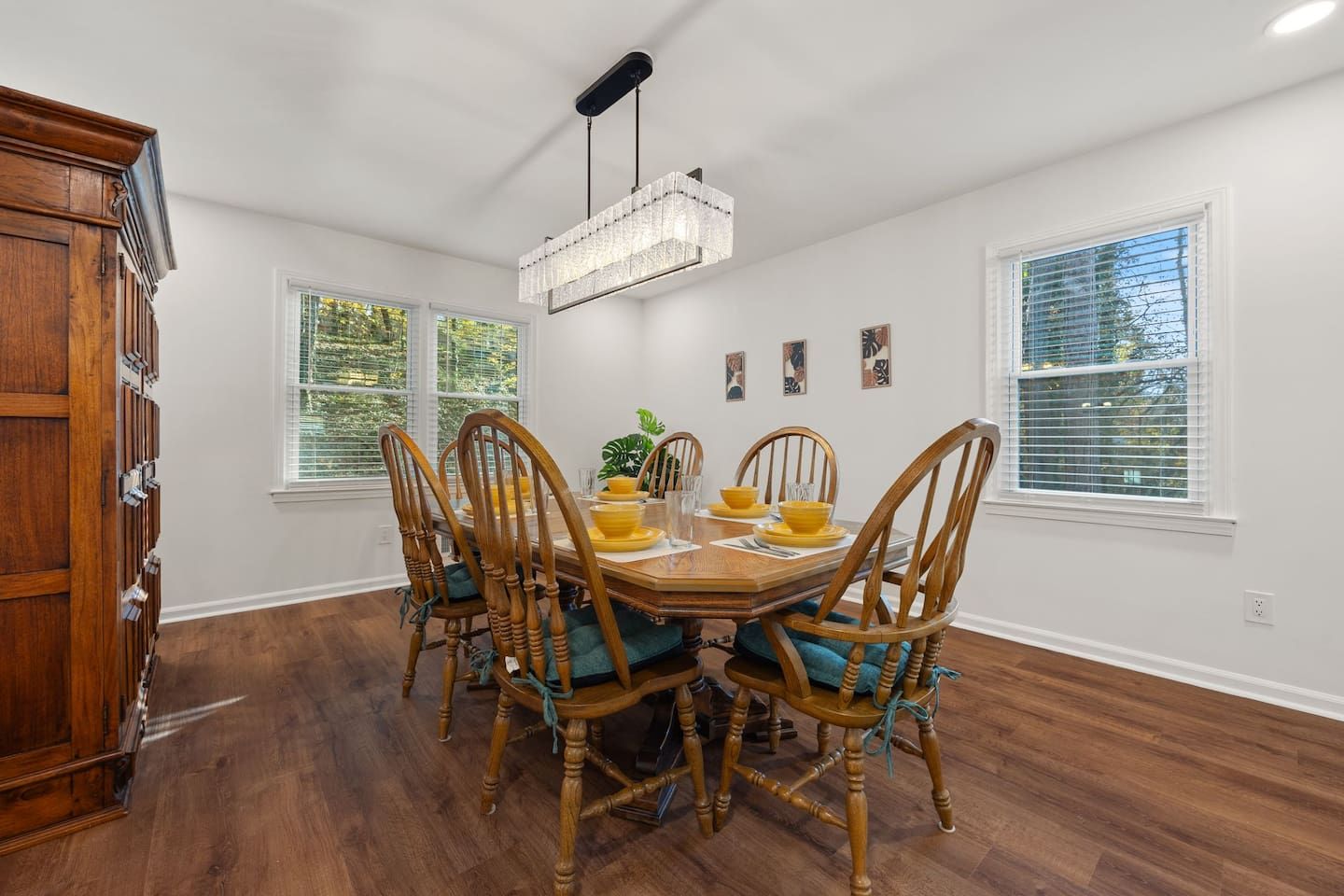 Une salle à manger avec une table en bois, des chaises et un lustre.