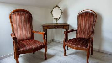 Deux fauteuils rembourrés avec des structures en bois, et une petite table avec un miroir placé entre les deux.