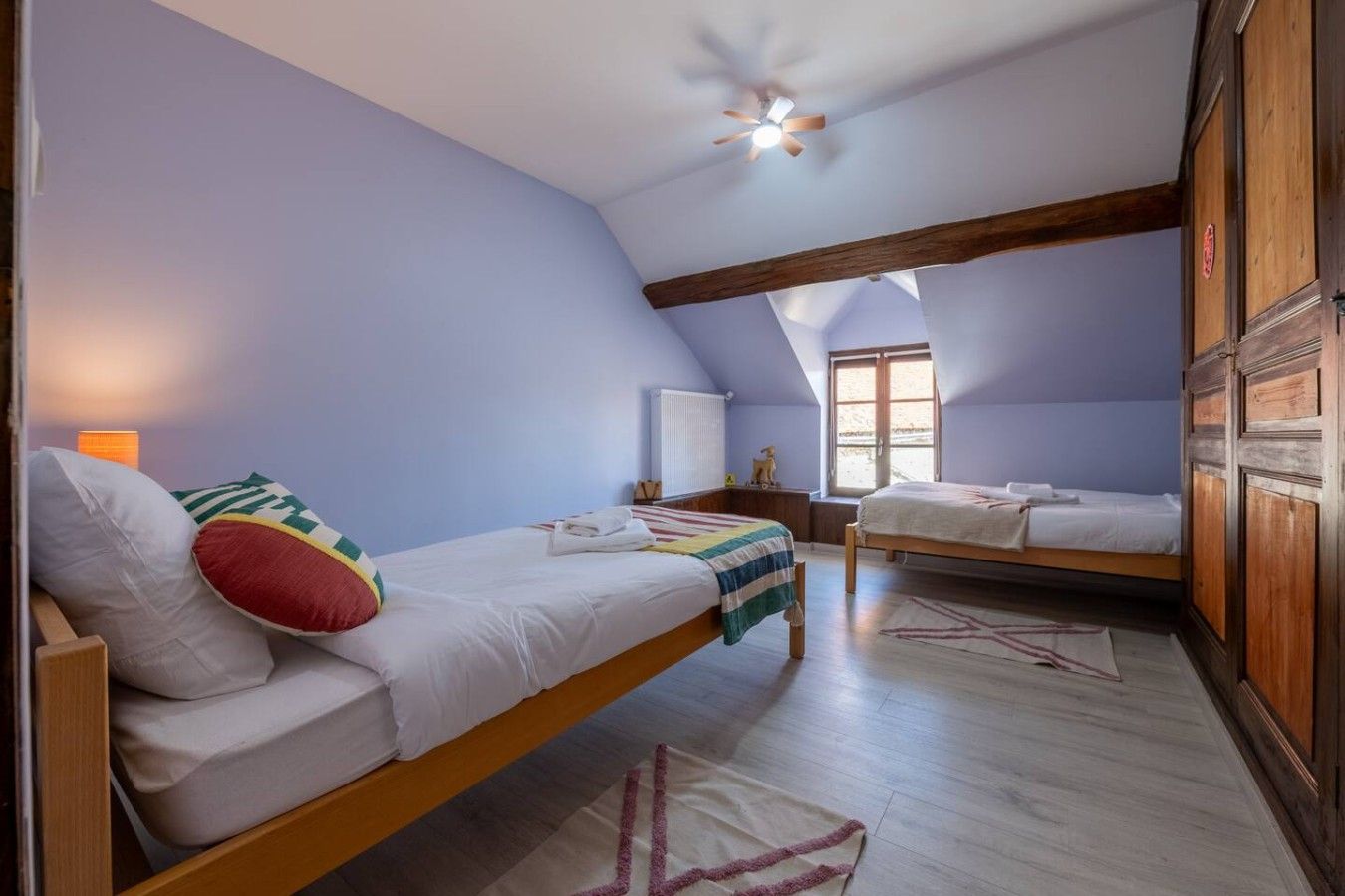 Een slaapkamer met twee bedden, een plafondventilator en een raam.