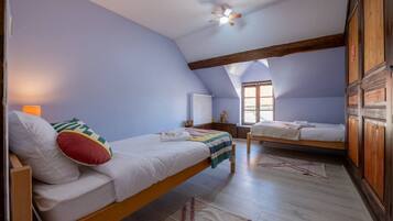 Een slaapkamer met twee bedden, een plafondventilator en een raam.