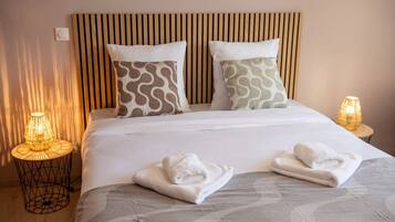 A hotel room with a bed, two pillows, two bedside lamps, and two towels on the bed.