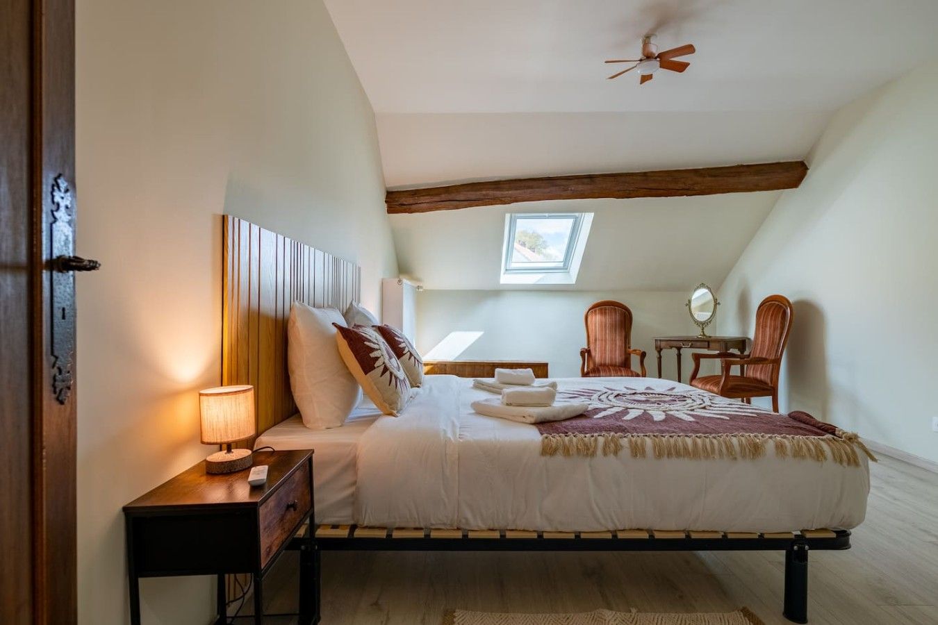 Ein Schlafzimmer mit Bett, Nachttisch, Lampe und Deckenventilator.