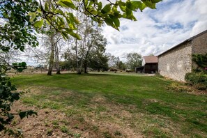 Un pati enjardinat amb arbres i un edifici de pedra.