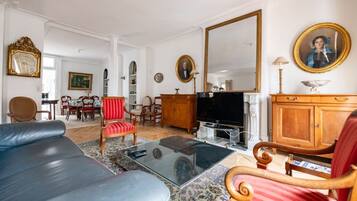 Un salon avec un canapé, des fauteuils, un téléviseur et une cheminée.