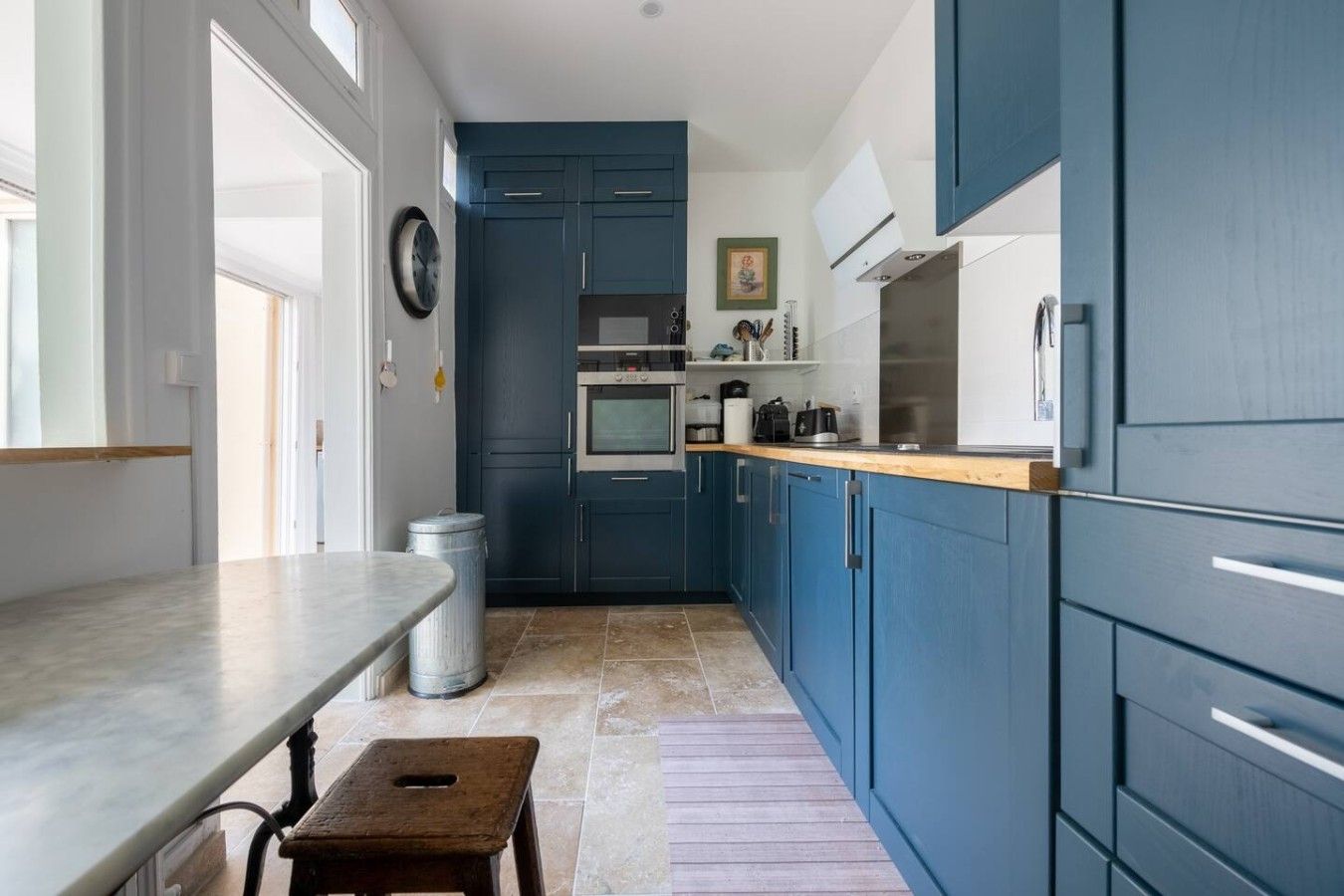 A kitchen with blue cabinets, a wooden countertop, a sink, and a stove.