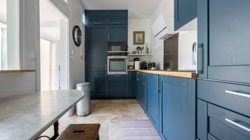 A kitchen with blue cabinets, a wooden countertop, a sink, and a stove.
