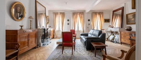 Un salón amplio con chimenea, sofá de cuero y un sillón rojo.