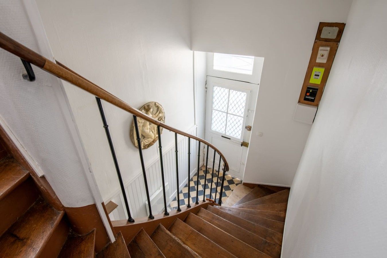 A wooden staircase with a handrail leading to a door with a window.