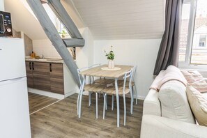 A compact living space with a kitchenette, a dining area with a table and chairs, and a sofa.