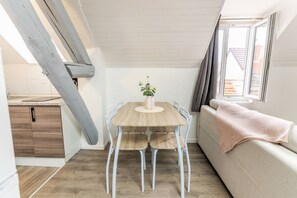 Un comedor acogedor con una mesa y sillas de madera, una planta en maceta y un sofá con una manta.