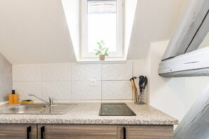 Una cocina con encimera de granito, un fregadero, una ventana con planta y un tragaluz.