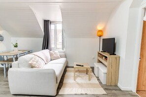 A modern living room with a sofa, a coffee table, a TV, and a lamp.