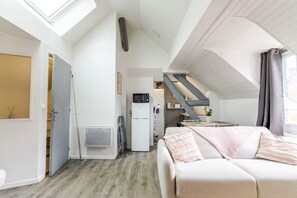 Un espacio habitable compacto con kitchenette, un sofá y una escalera que conduce a un nivel superior.