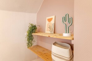 A corner with a wooden shelf holding a framed artwork and a green cactus sculpture. - The central building, renovated and bright (Romilly-sur-Seine)