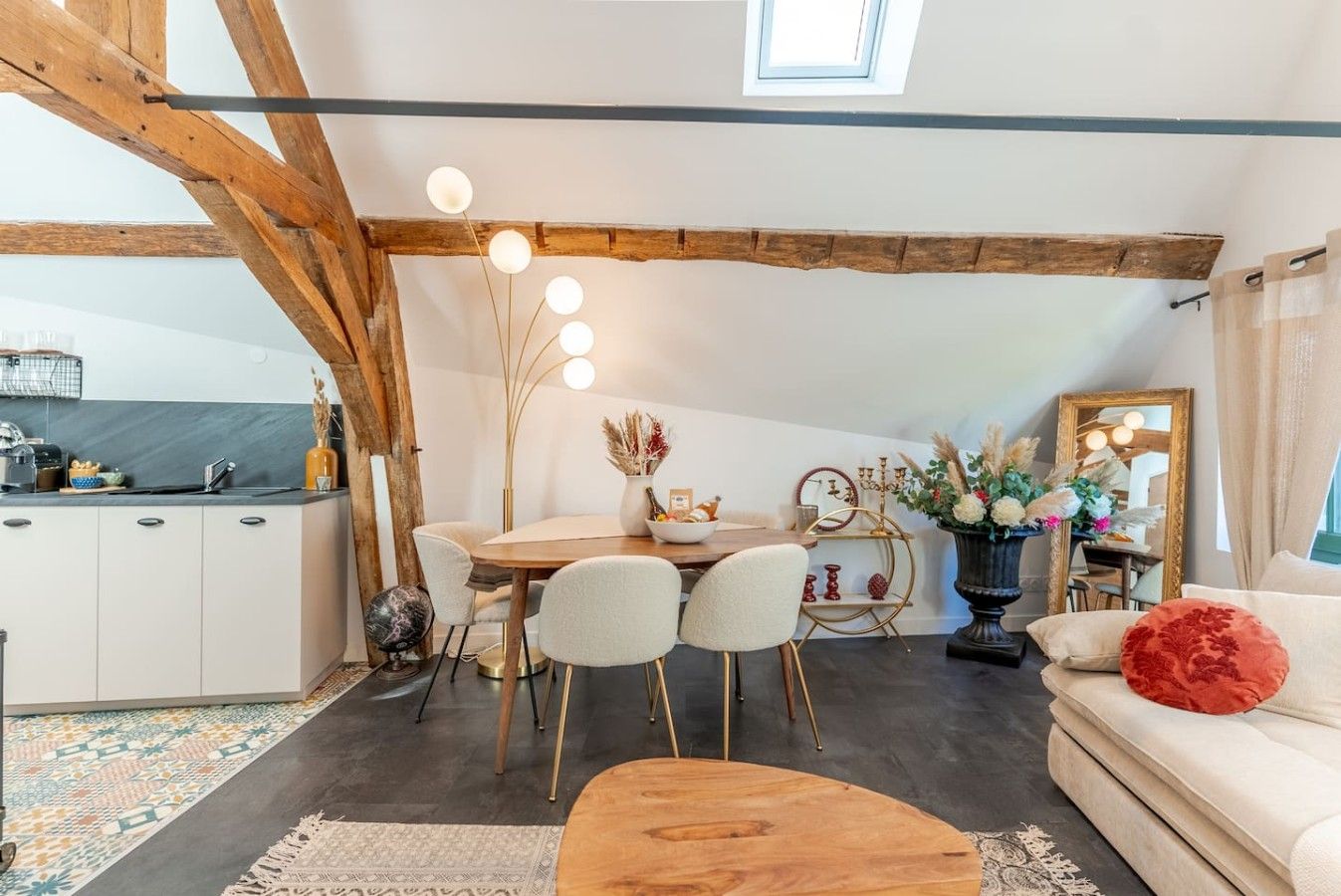A cozy loft-style living space with a dining area, kitchen, and a large window.