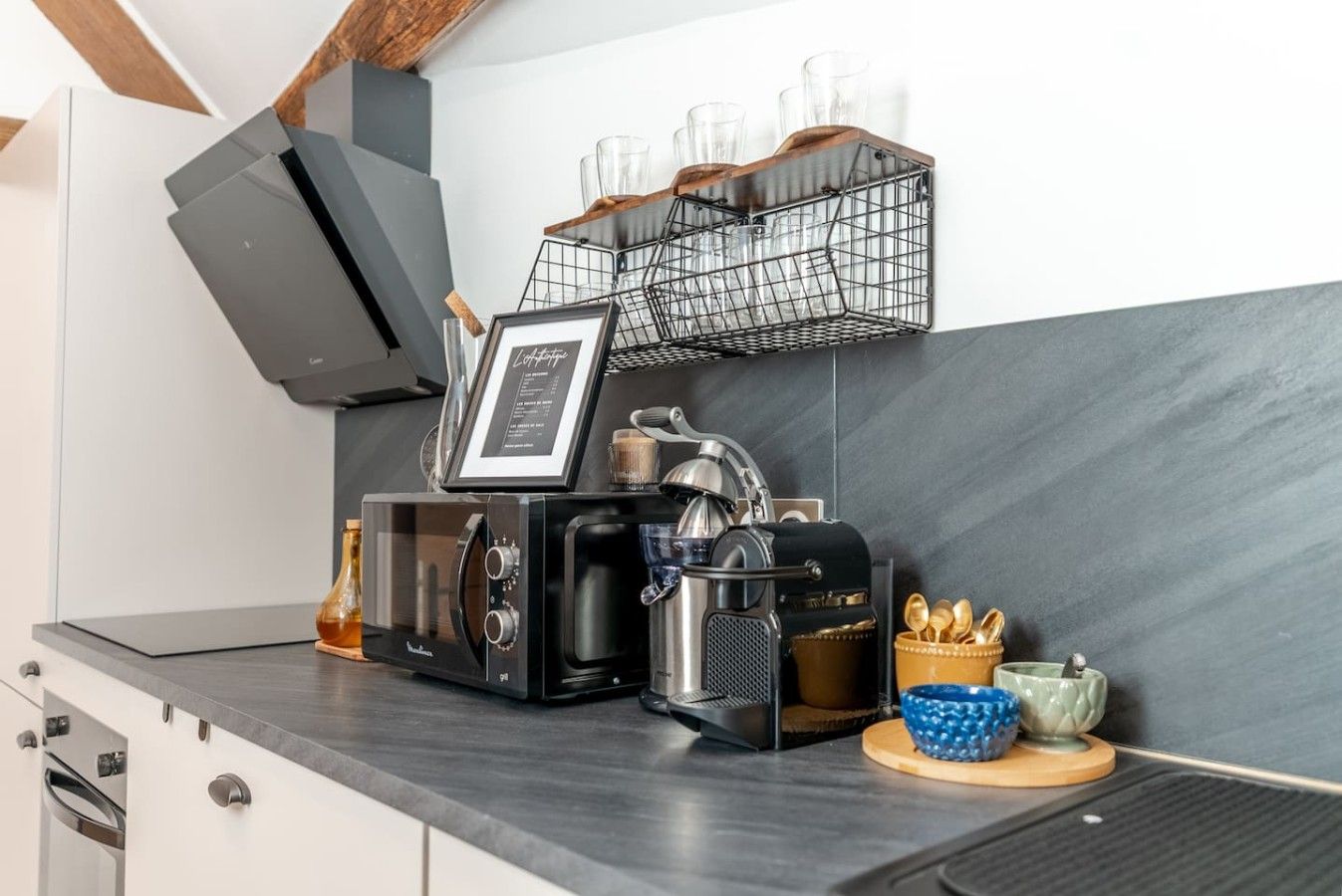 Een keuken met een koffieapparaat, waterkoker, broodrooster en een koffiemolen op het aanrecht.