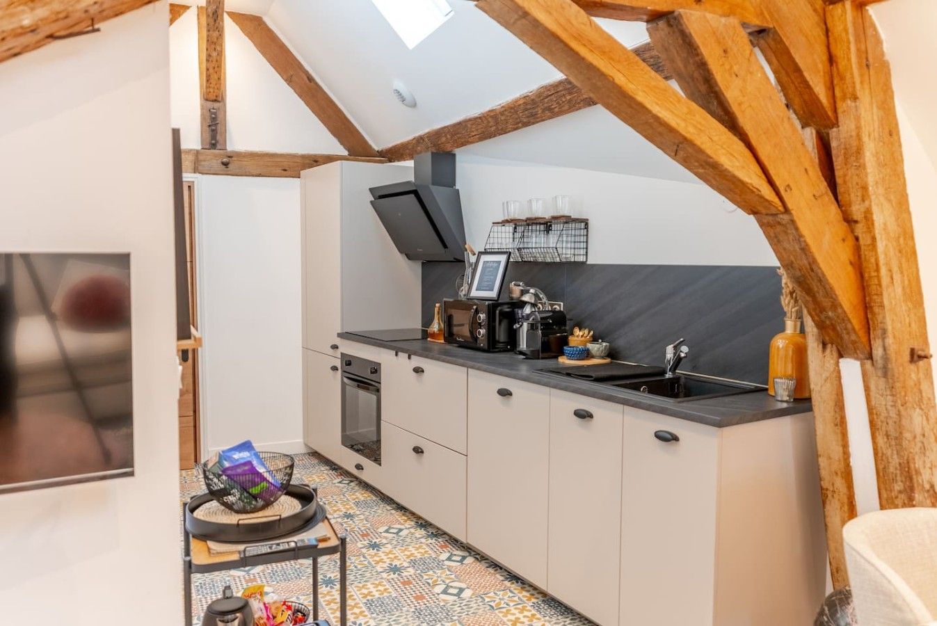 A compact kitchen with a built-in oven, a coffee machine, and a sink.