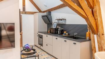 A compact kitchen with a built-in oven, a coffee machine, and a sink.
