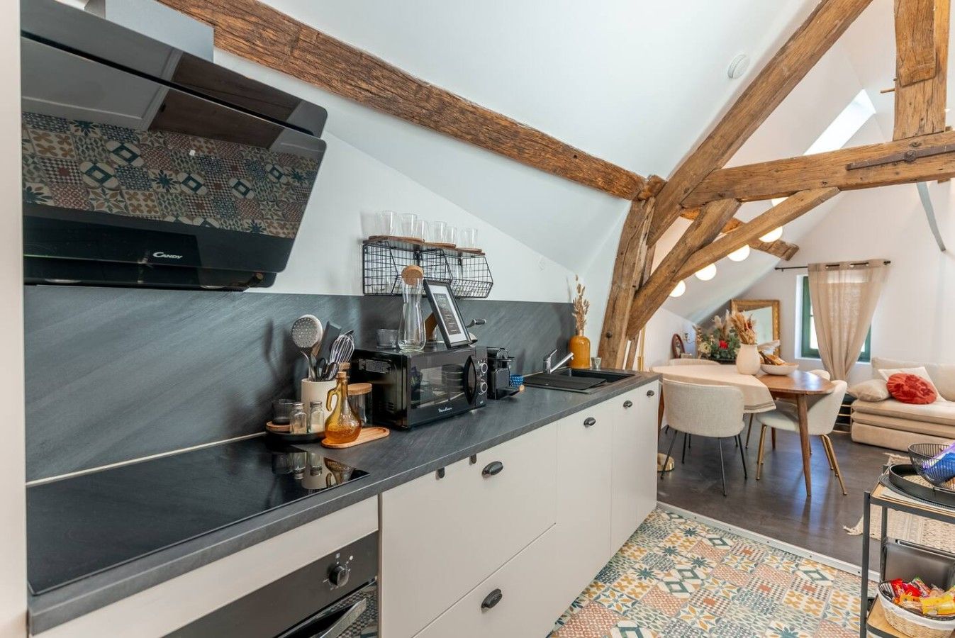 A modern kitchen with a black countertop, white cabinets, and a wooden ceiling.
