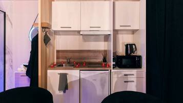A compact kitchen with white cabinets, a black microwave, and a stove.