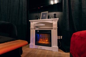 A room with a white fireplace, a framed quote on the mantel, and a television mounted on the wall.
