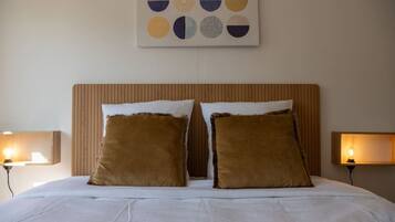 A hotel room with a large bed, two pillows, a headboard, and a wall art piece above the bed.