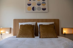 Ein Hotelzimmer mit einem großen Bett, zwei Kissen, einem Kopfteil und einem Kunstwerk darüber.