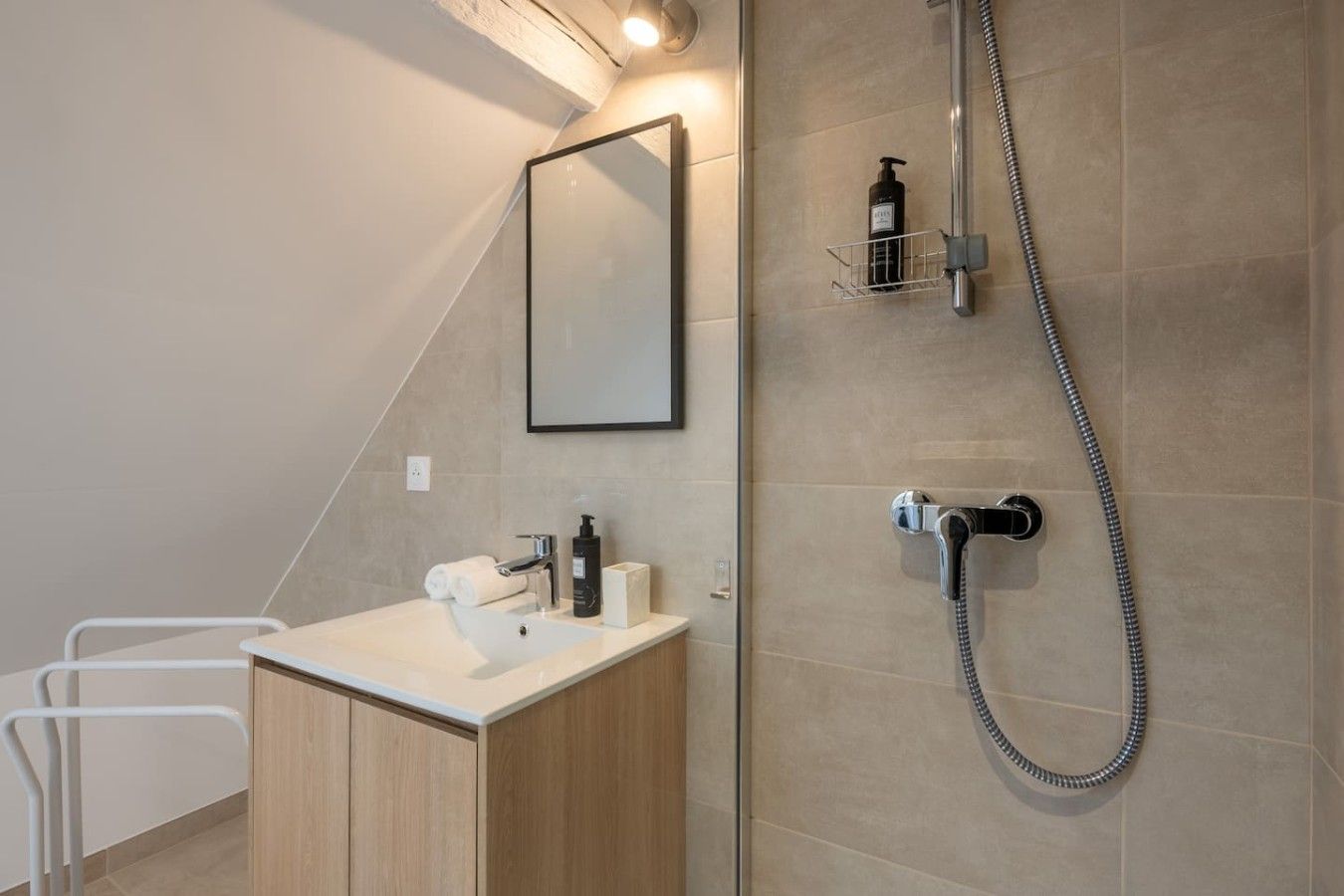 Une salle de bain moderne avec une douche, un lavabo et un miroir.